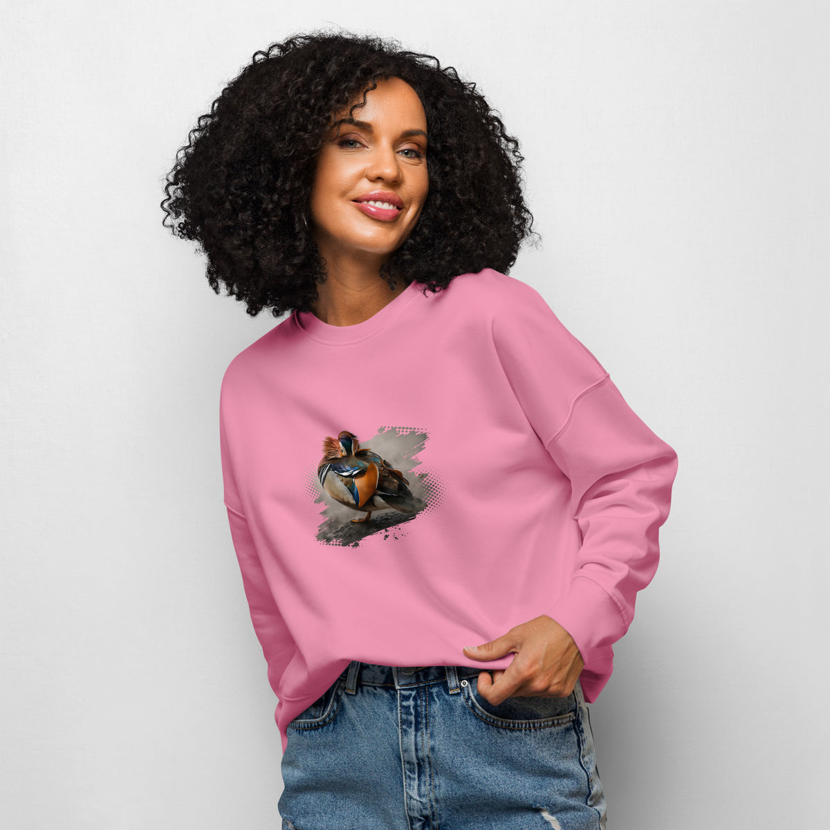 A woman wearing a cozy pink sustainable organic cotton sweatshirt featuring a vibrant Mandarin duck wildlife photograph by Jarno Virtanen.