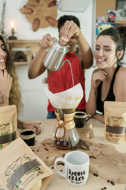 Two happy friends laughing and holding coffee mugs, symbolizing the health benefits of friendship and social connection.