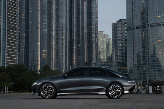 A sleek electric car driving on a clean city street surrounded by green trees, representing the improvement of urban air quality.