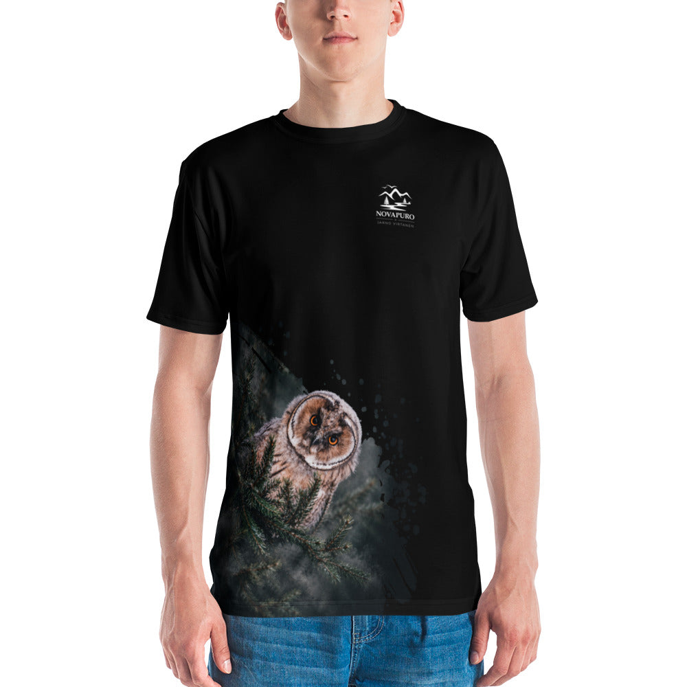 A man wearing the black Novapuro x Jarno Virtanen premium men's t-shirt featuring a Nordic long-eared owl chick print on the lower side.