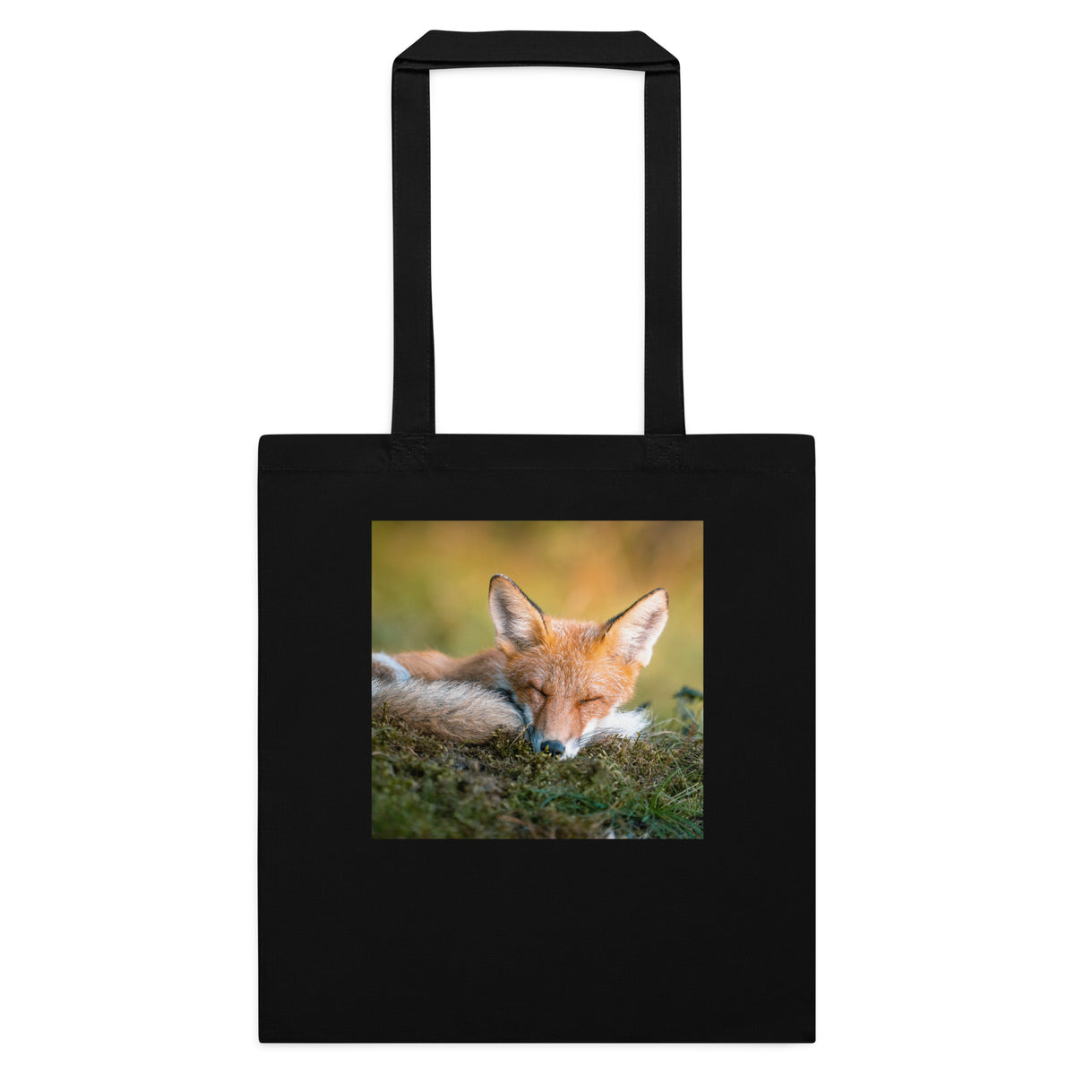 A black cotton tote bag featuring an original photograph of a resting red fox in the morning sun by Mikko Monto.