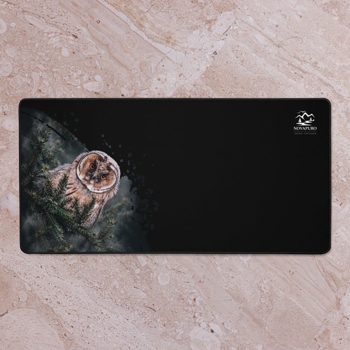 A black Novapuro x Jarno Virtanen desk mat featuring a Nordic long-eared owl chick print on the left side and a small logo on the right.