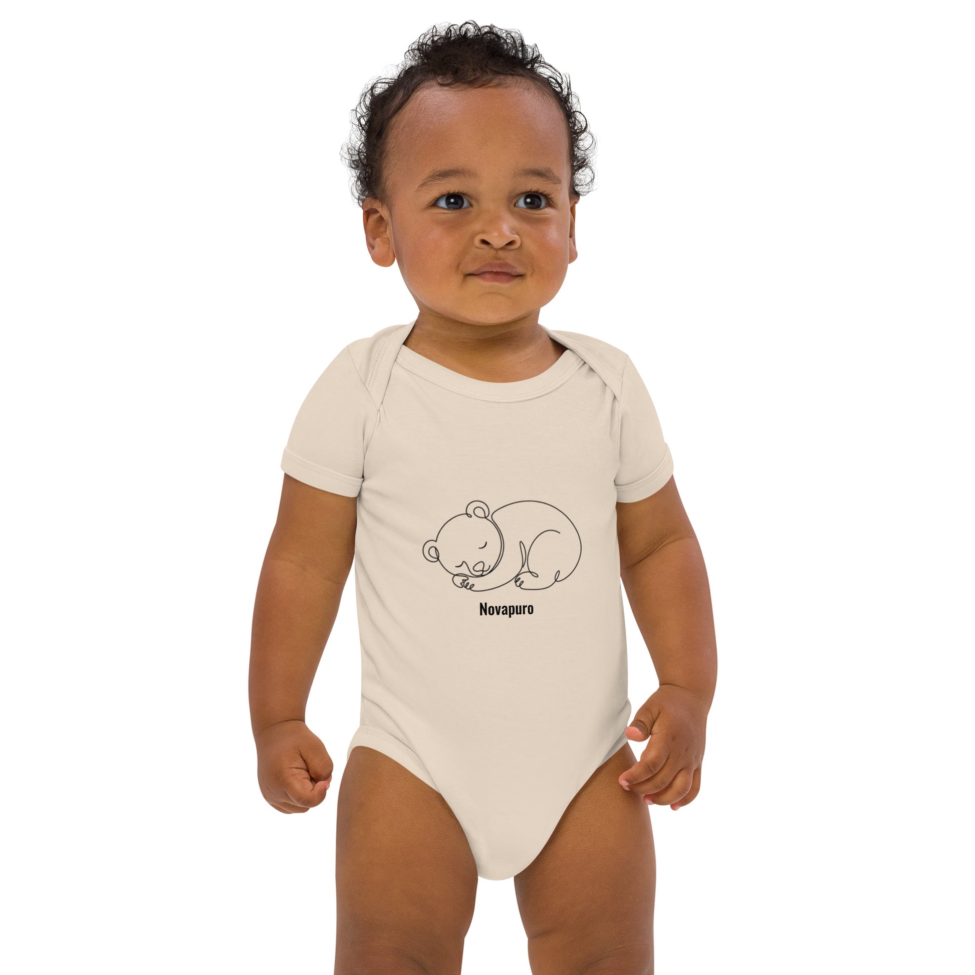 Baby wearing a sand-colored organic cotton bodysuit featuring a minimalist continuous line art of a sleeping bear and the Novapuro logo.