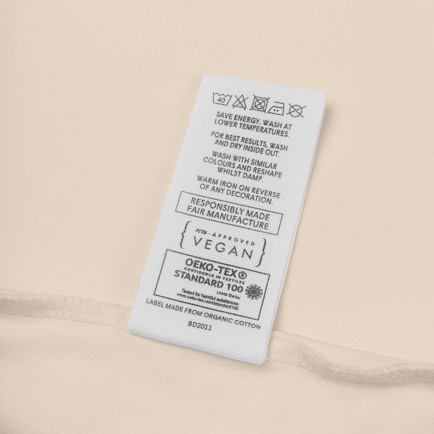 Close-up of the organic cotton baby bodysuit care label showing sustainable material details and washing instructions