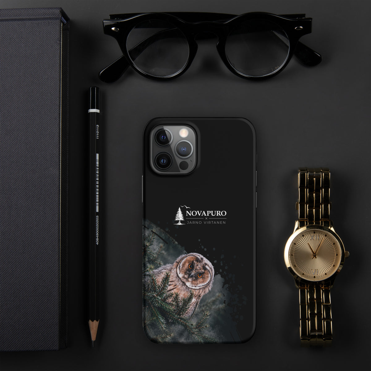 A black snap case for iPhone featuring a Nordic long-eared owl chick print by Jarno Virtanen, displayed flat on a dark surface next to glasses and a watch.
