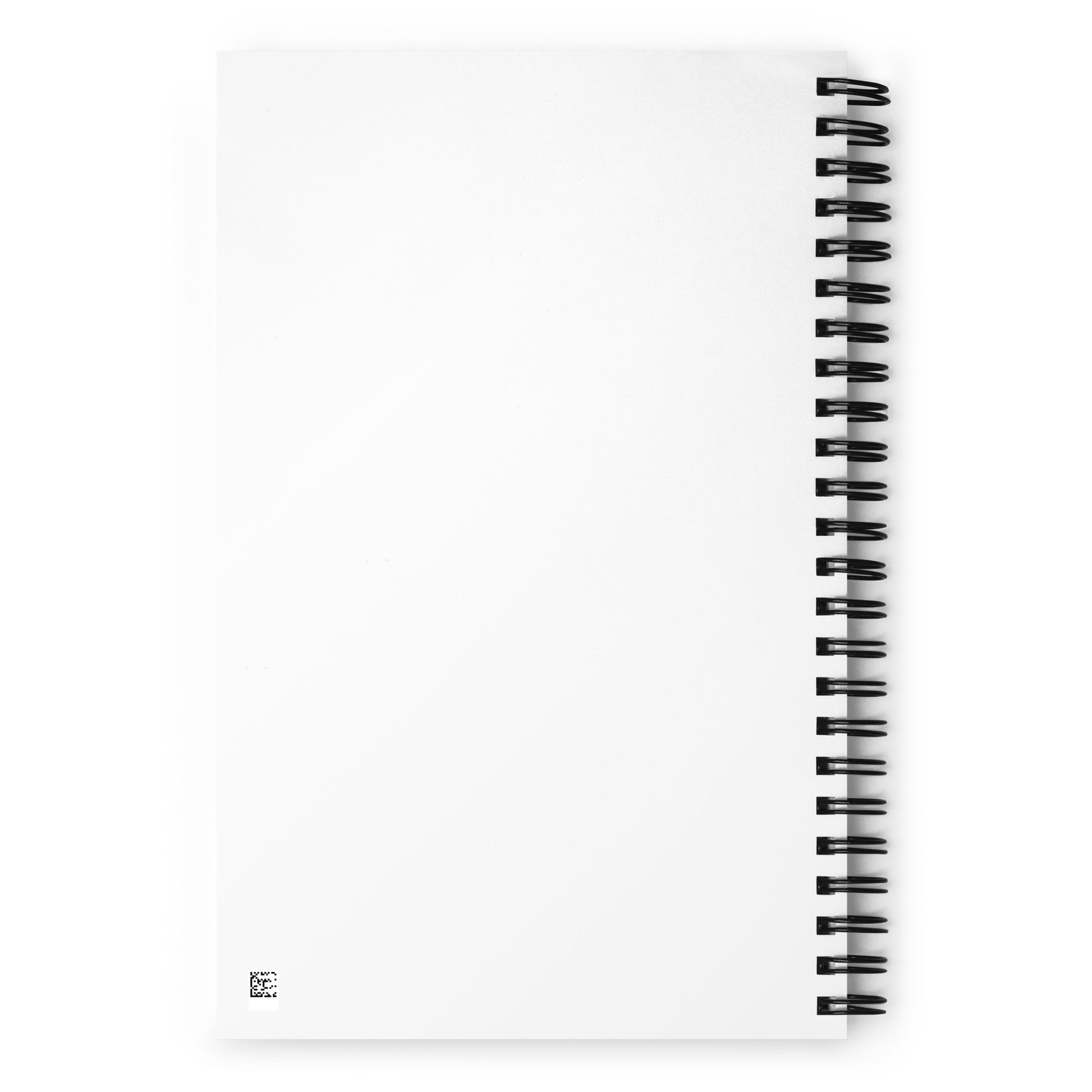 A white spiral-bound notebook laying flat on a desk next to a coffee cup, featuring a minimalist charcoal grey line art illustration of a Nordic lake reflecting a pine tree with the text "STILLNESS".