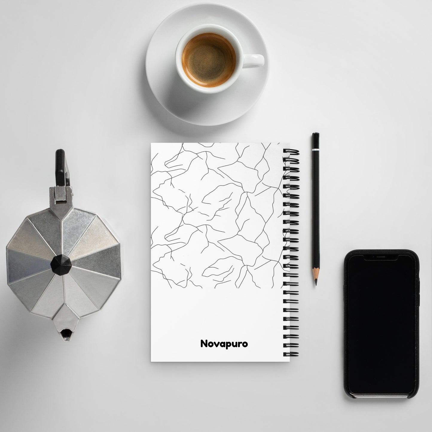 Minimalist spiral notebook with black and white Spring Ice abstract pattern and Novapuro logo on a clean desk with coffee.