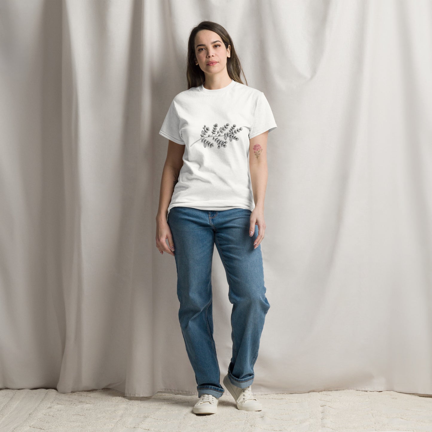 Front view of a white classic t-shirt featuring an elegant minimalist black ink illustration of a Nordic spruce branch centered on the chest.