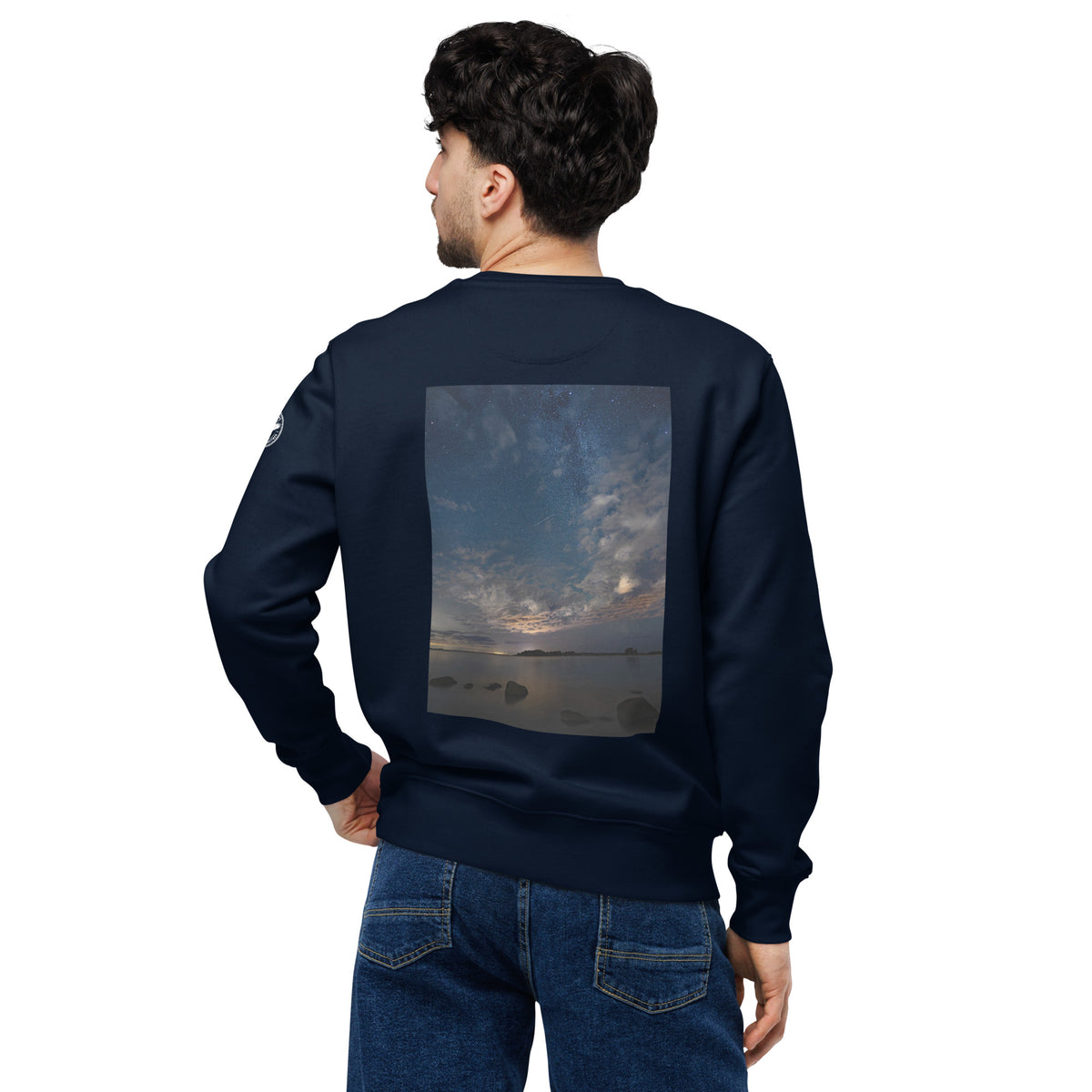 A person wearing the dark navy Novapuro x Annette Thomé-Marttinen 'Nordic Night Sky' organic sweatshirt, featuring a beautiful photograph of a starry night and a shooting star over a calm lake.