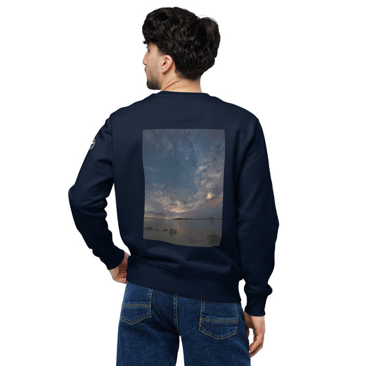 A person wearing the dark navy Novapuro x Annette Thomé-Marttinen 'Nordic Night Sky' organic sweatshirt, featuring a beautiful photograph of a starry night and a shooting star over a calm lake.