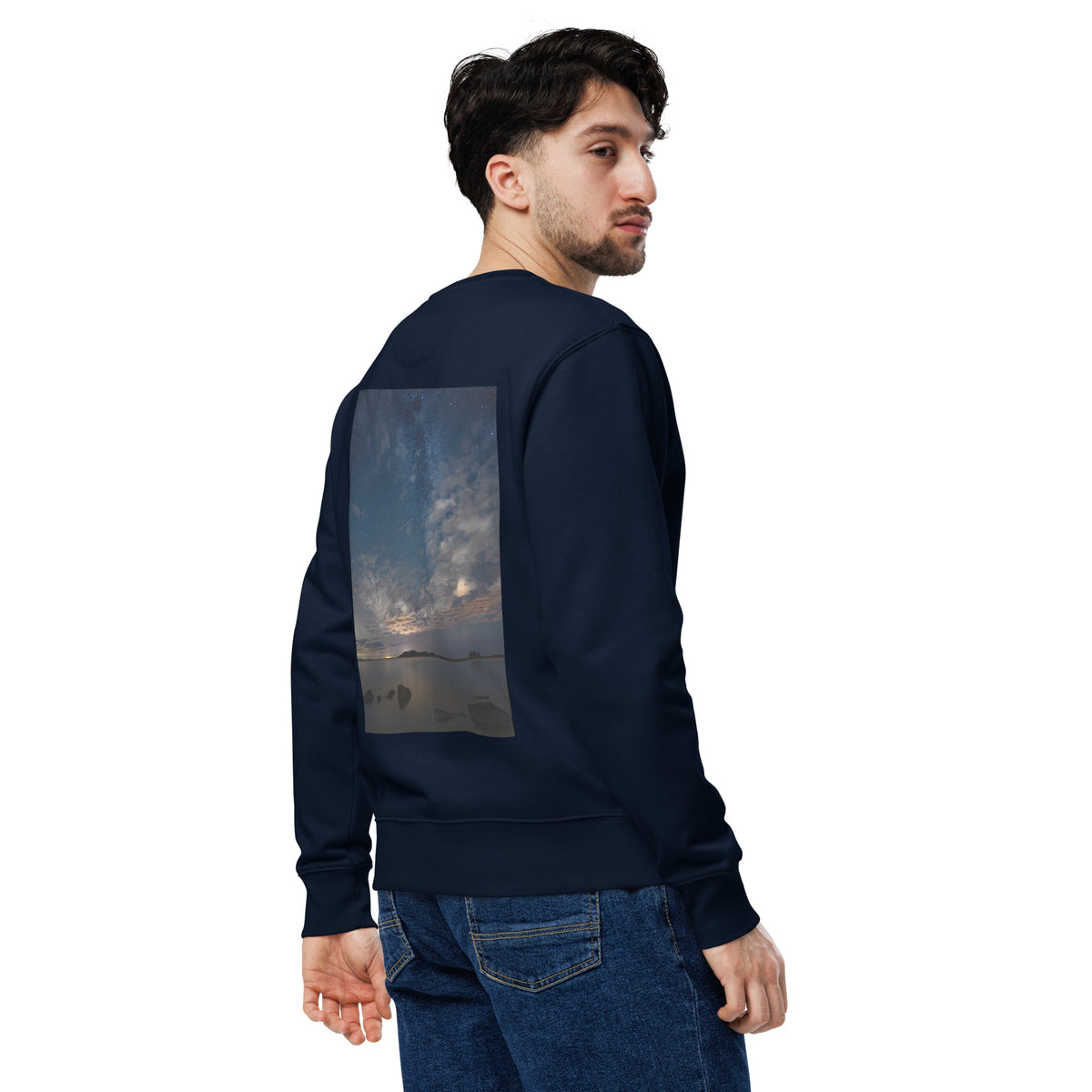 A person wearing the dark navy Novapuro x Annette Thomé-Marttinen 'Nordic Night Sky' organic sweatshirt, featuring a beautiful photograph of a starry night and a shooting star over a calm lake.