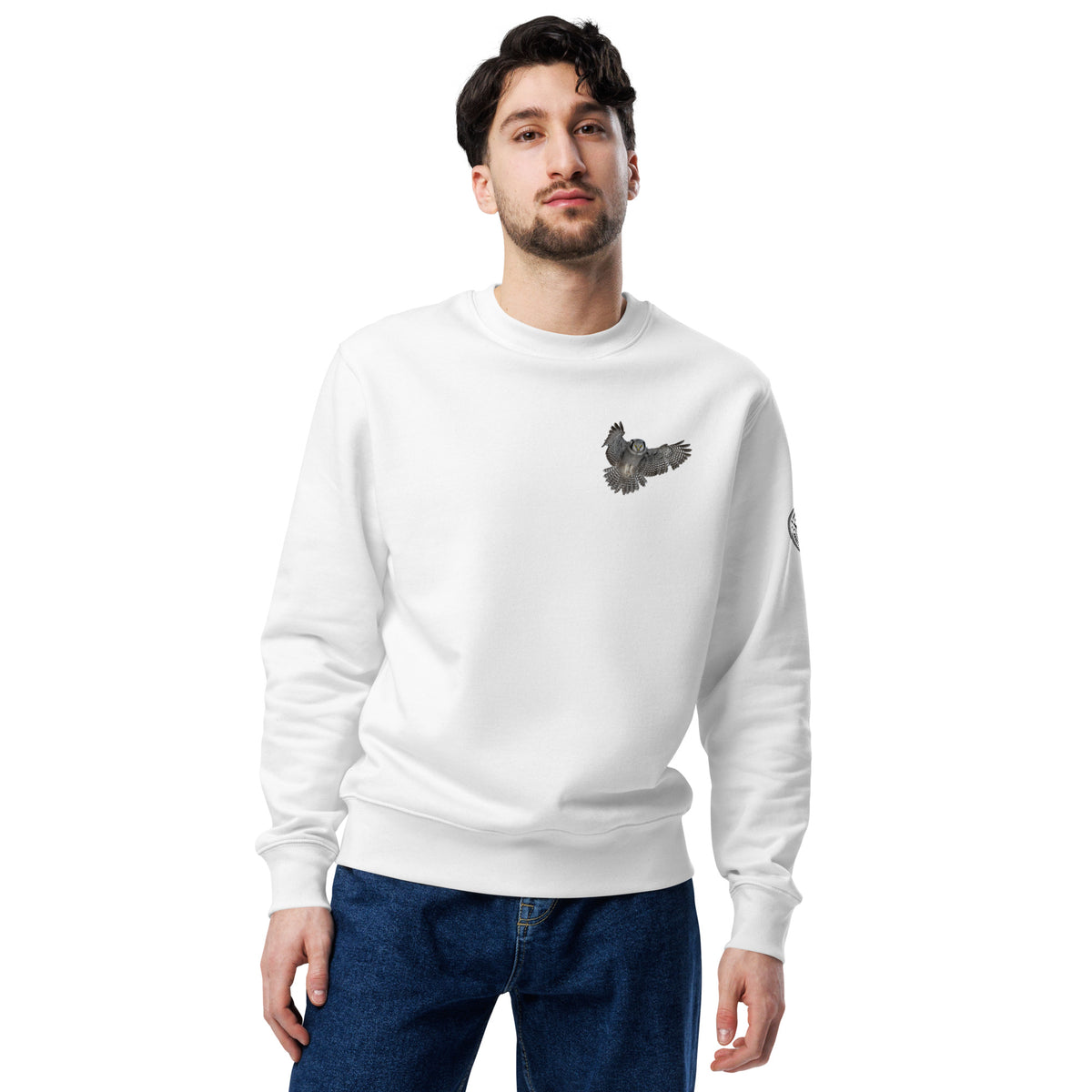 Front view of a person wearing a white unisex organic eco sweatshirt featuring a small Northern Hawk Owl print on the left chest by Annette Thome Marttinen x Novapuro.