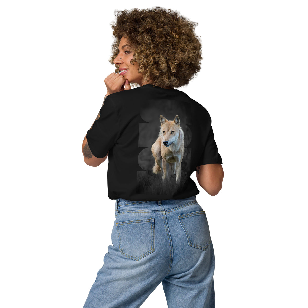 Auli Leivonen wearing a black Novapuro organic cotton t-shirt with a majestic Nordic wolf photography print on the back, standing outdoors.