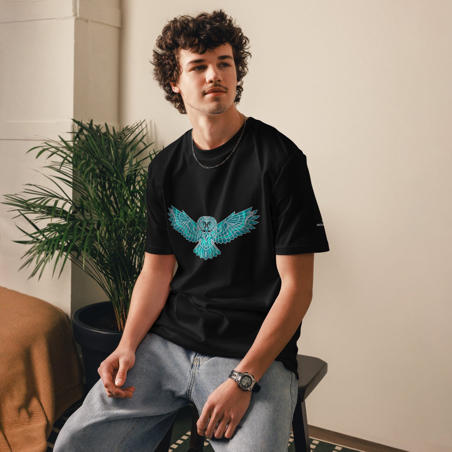 Model wearing the black Novapuro organic cotton t-shirt featuring a striking geometric teal owl print.