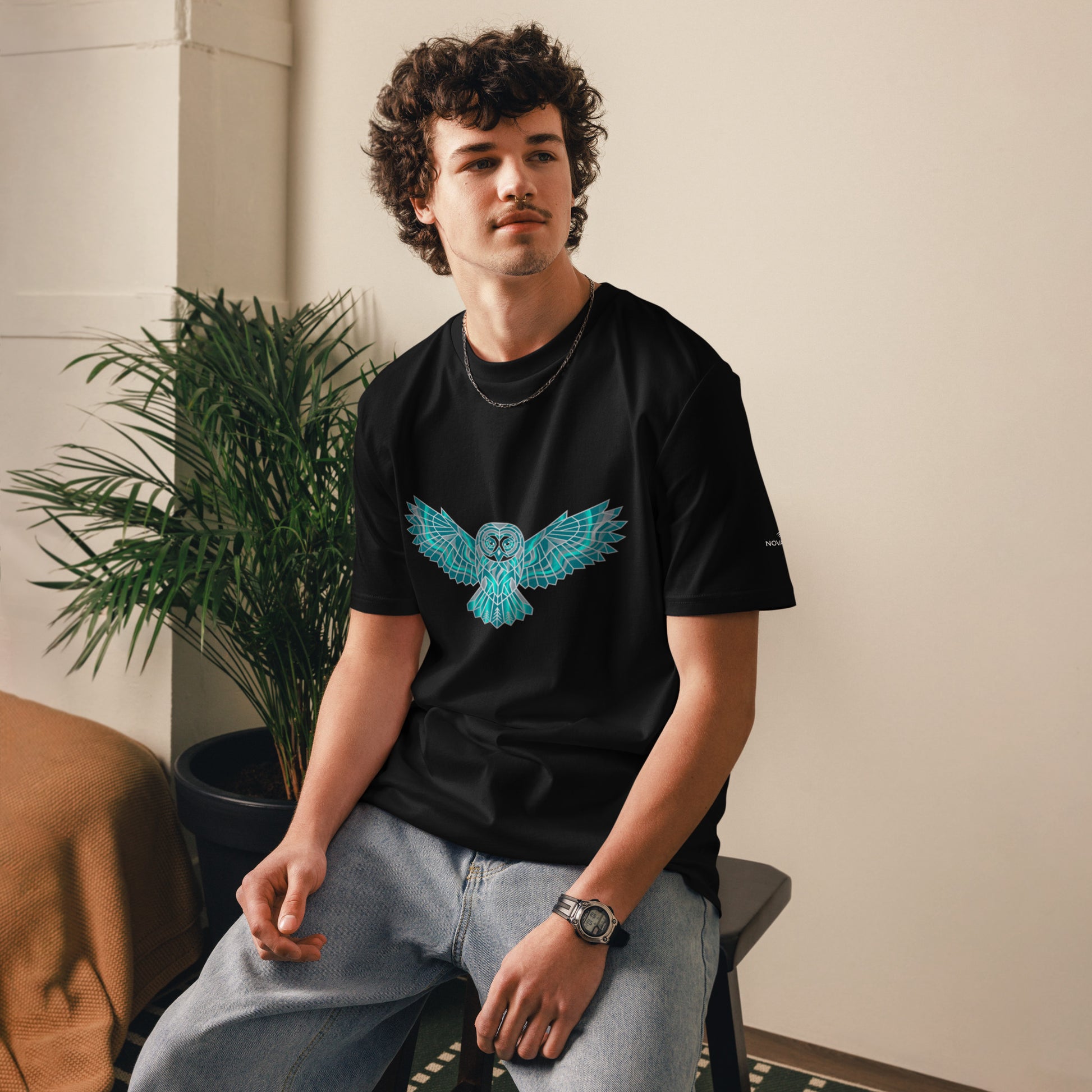 Model wearing the black Novapuro organic cotton t-shirt featuring a striking geometric teal owl print.