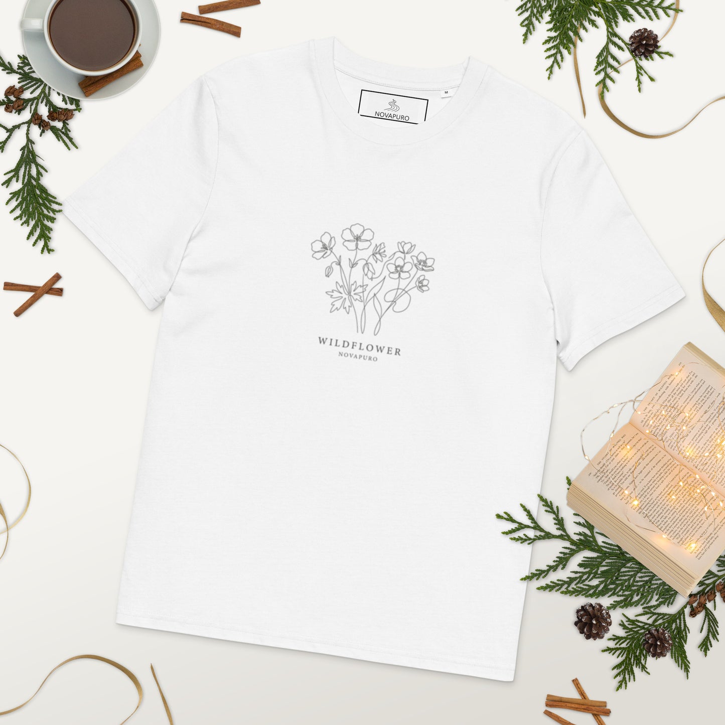 A woman wearing a crisp white premium organic cotton t-shirt featuring an elegant, minimalist single line art illustration of Nordic wildflowers.