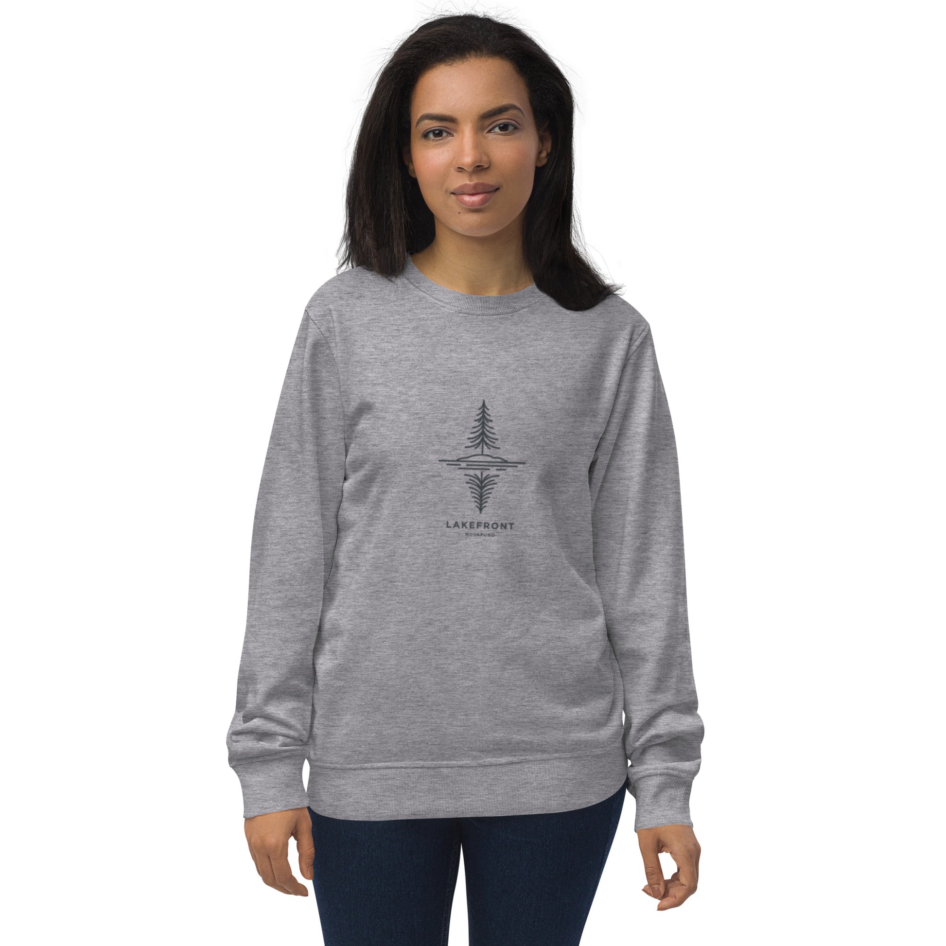 A model wearing a white premium organic sweatshirt featuring a minimalist line art illustration of a pine tree reflecting on a Nordic lake.