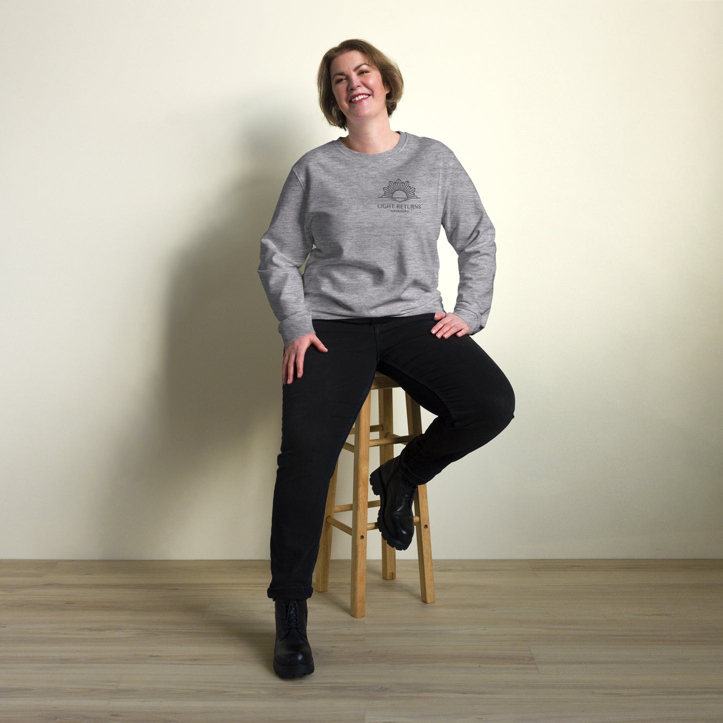 Minimalist sun graphic with 'Light Returns Novapuro' text on a grey or white eco-friendly organic cotton sweatshirt.