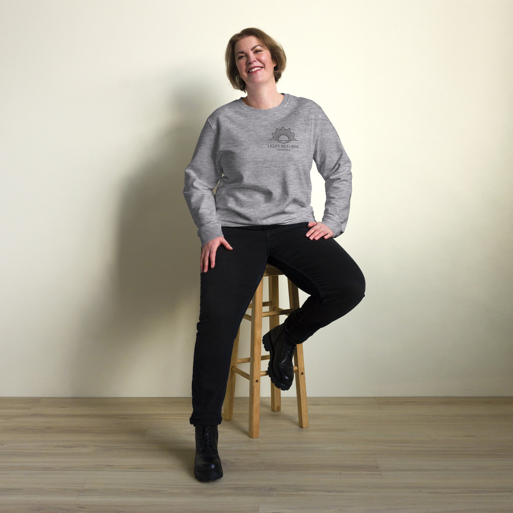 Minimalist sun graphic with 'Light Returns Novapuro' text on a grey or white eco-friendly organic cotton sweatshirt.