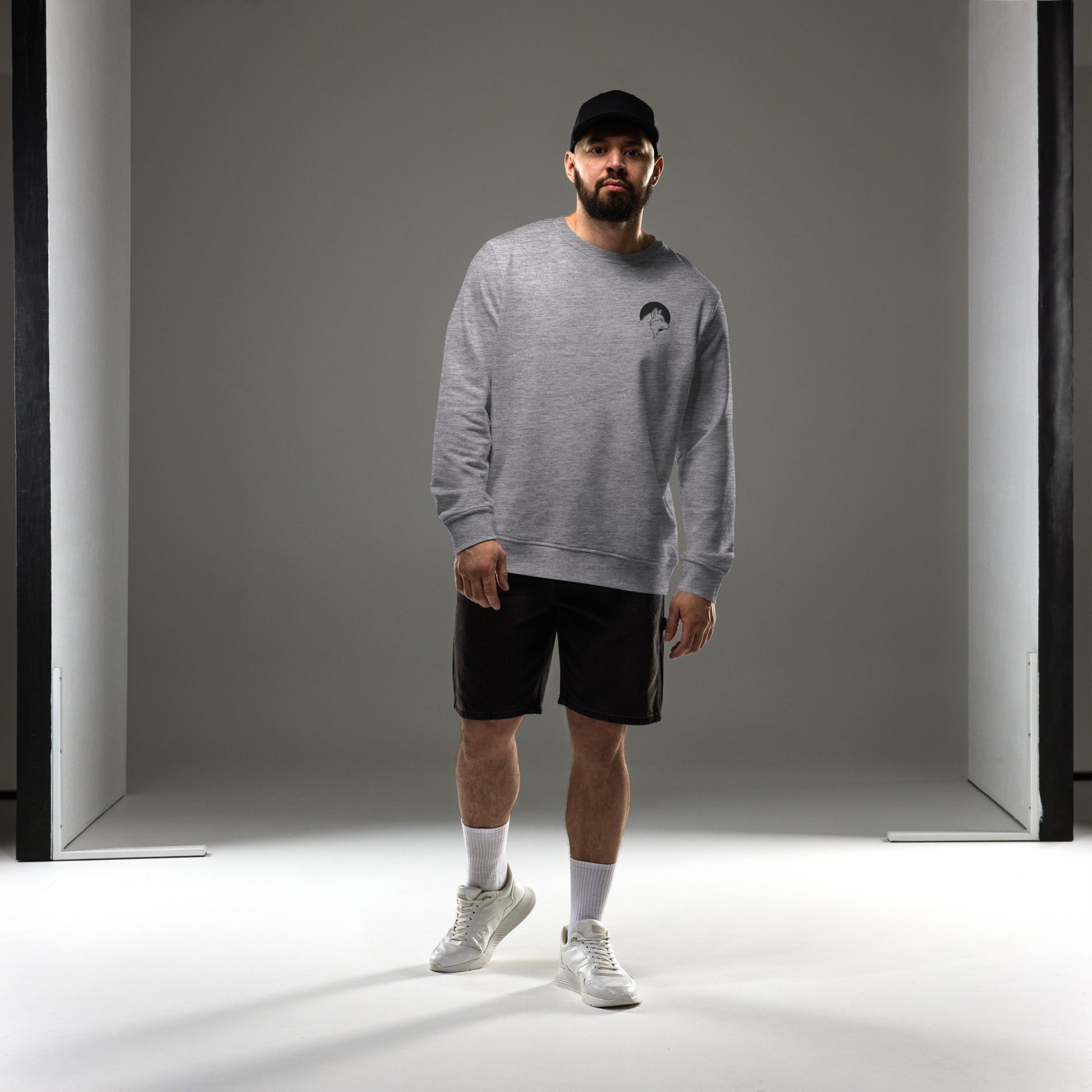 A man wearing a grey sustainable organic cotton sweatshirt with a minimalist wolf line art logo, demonstrating Nordic lifestyle fashion.