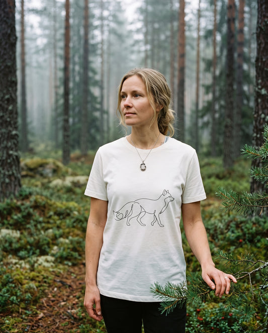 A woman enjoying the Nordic nature wearing Novapuro's off-white women's organic cotton Arctic Fox t-shirt. This ecological and sustainably made tee with a minimalist arctic fox print offers breathable comfort for both outdoor adventures and casual everyday wear.